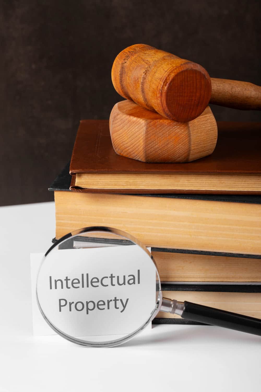 Intellectual Property (IP) Enforcement Strategy & Pre-Litigation Counseling A hand stamping 'PATENTED HIGH QUALITY' on a notebook with handwritten notes, placed on a wooden desk with a leather folder and a cup in the background.