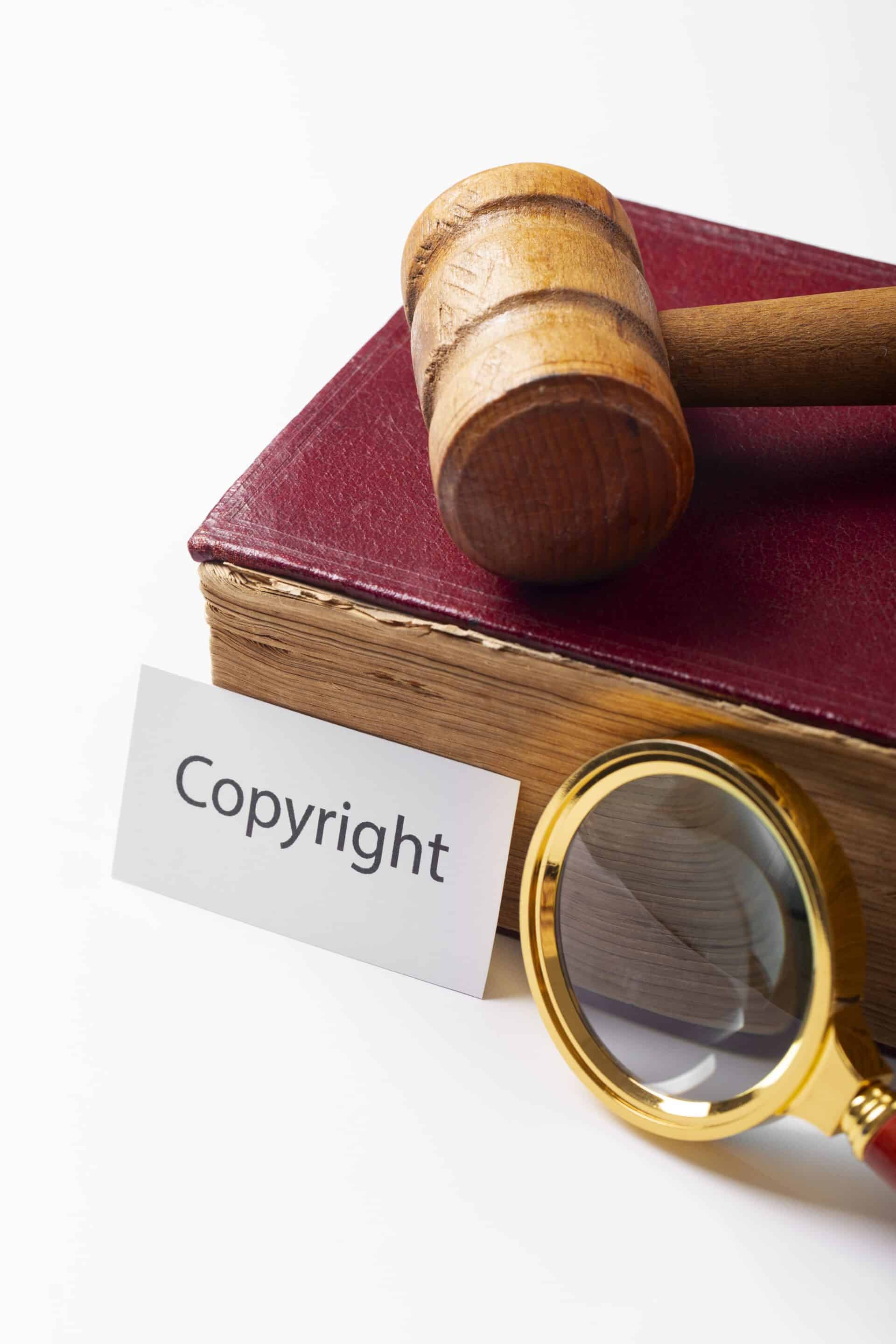 copyrights A hand stamping 'PATENTED HIGH QUALITY' on a notebook with handwritten notes, placed on a wooden desk with a leather folder and a cup in the background.